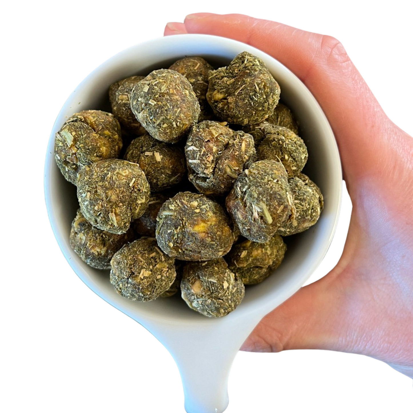 Teff treats displayed with a person holding them in a teacup for size reference.