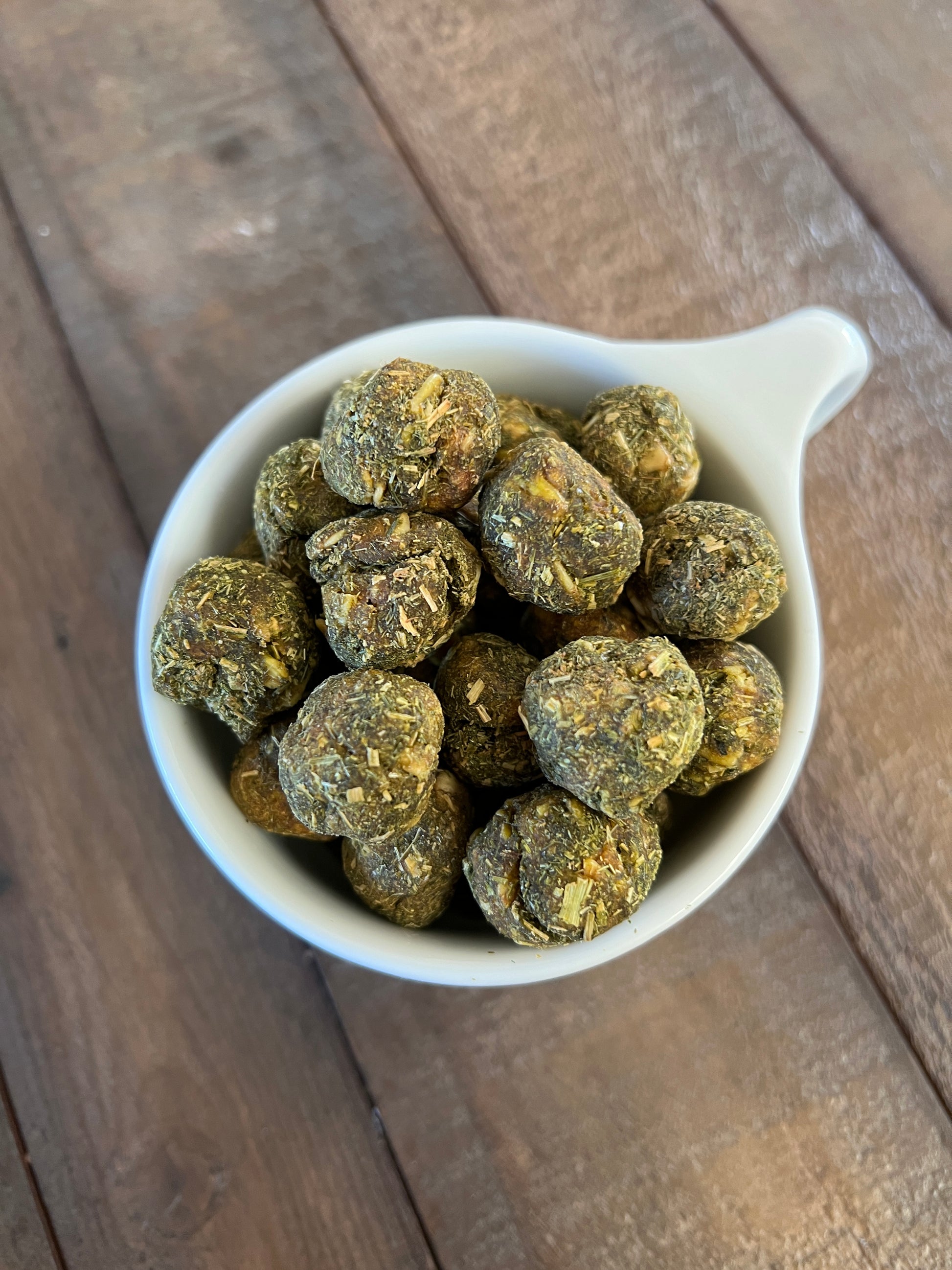 Training treats shown in a white teacup on a table for size reference. These treats are on the smaller side, great for overweight horses or for owners looking for a low sugar but tasty treat option.